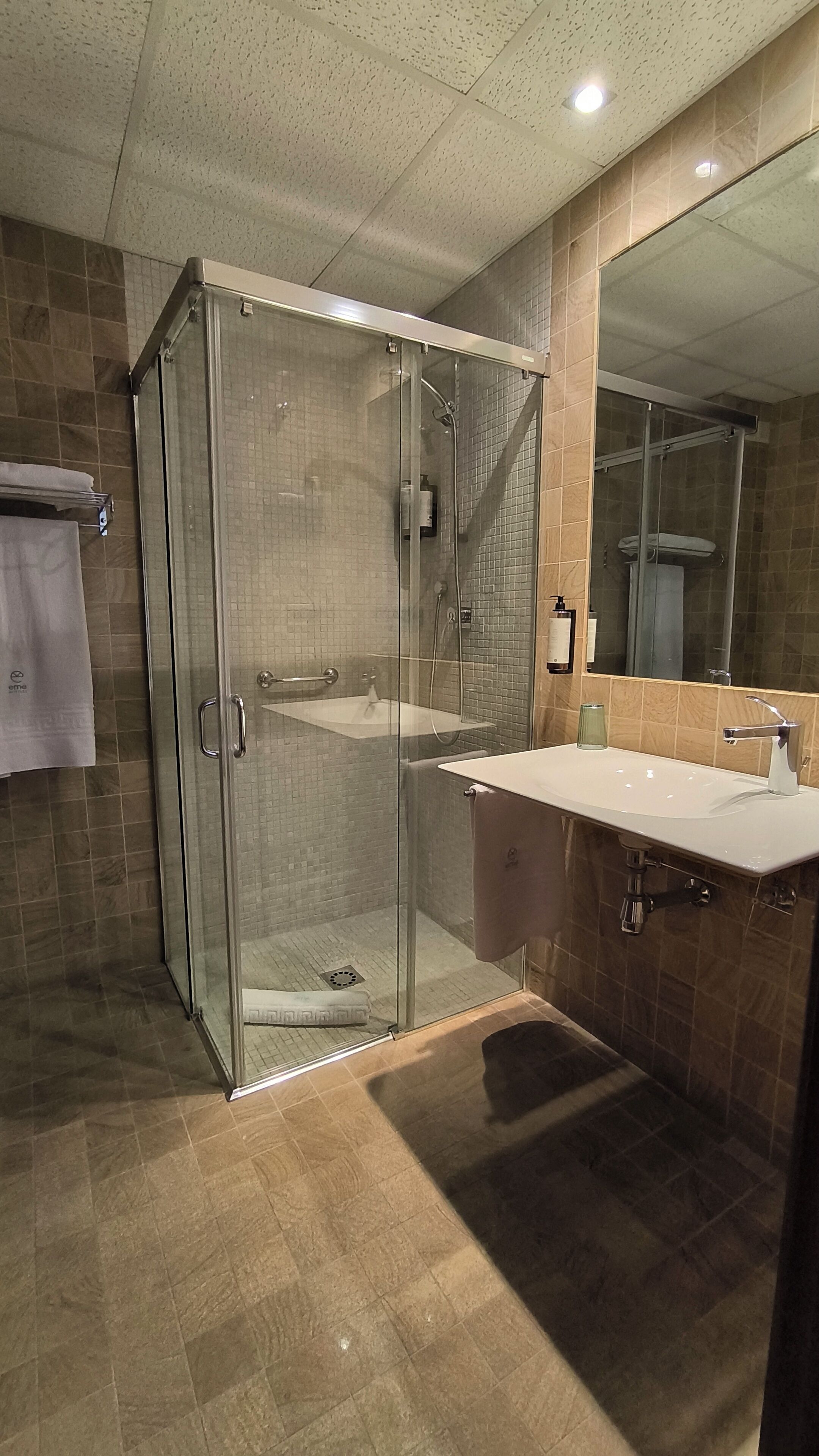 Une salle de bain moderne avec une douche à parois de verre, un lavabo et un miroir.