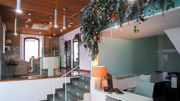 A modern interior with a staircase, a desk with a computer, and hanging plants. - Hotel Baeza Monumental by eme Hoteles (Baeza)