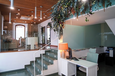 A modern interior with a staircase, a desk with a computer, and hanging plants.