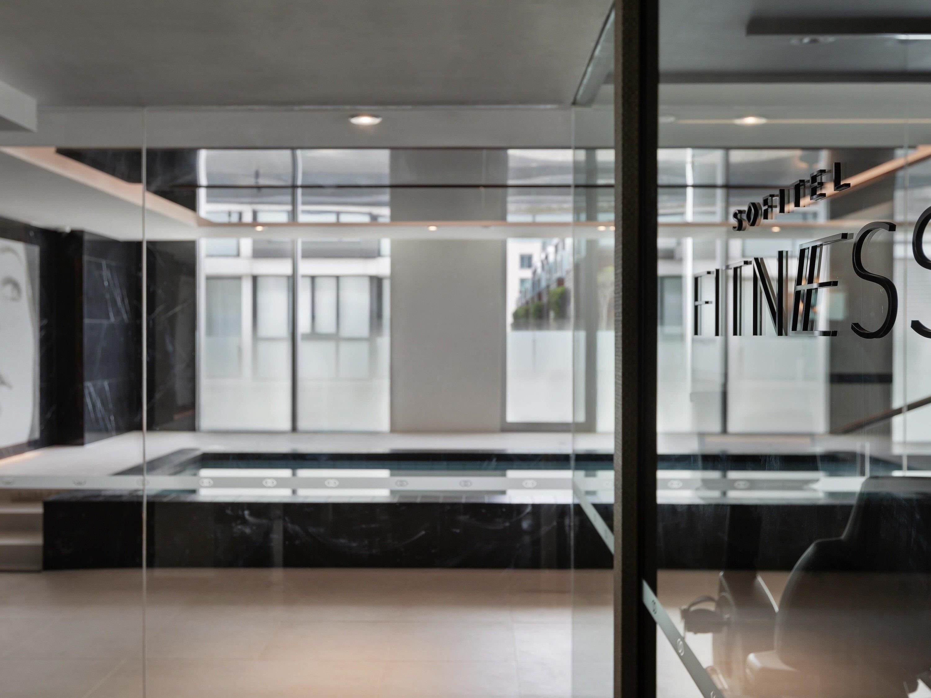 A modern interior with a glass partition displaying the words "SOFITEL FITNESS".