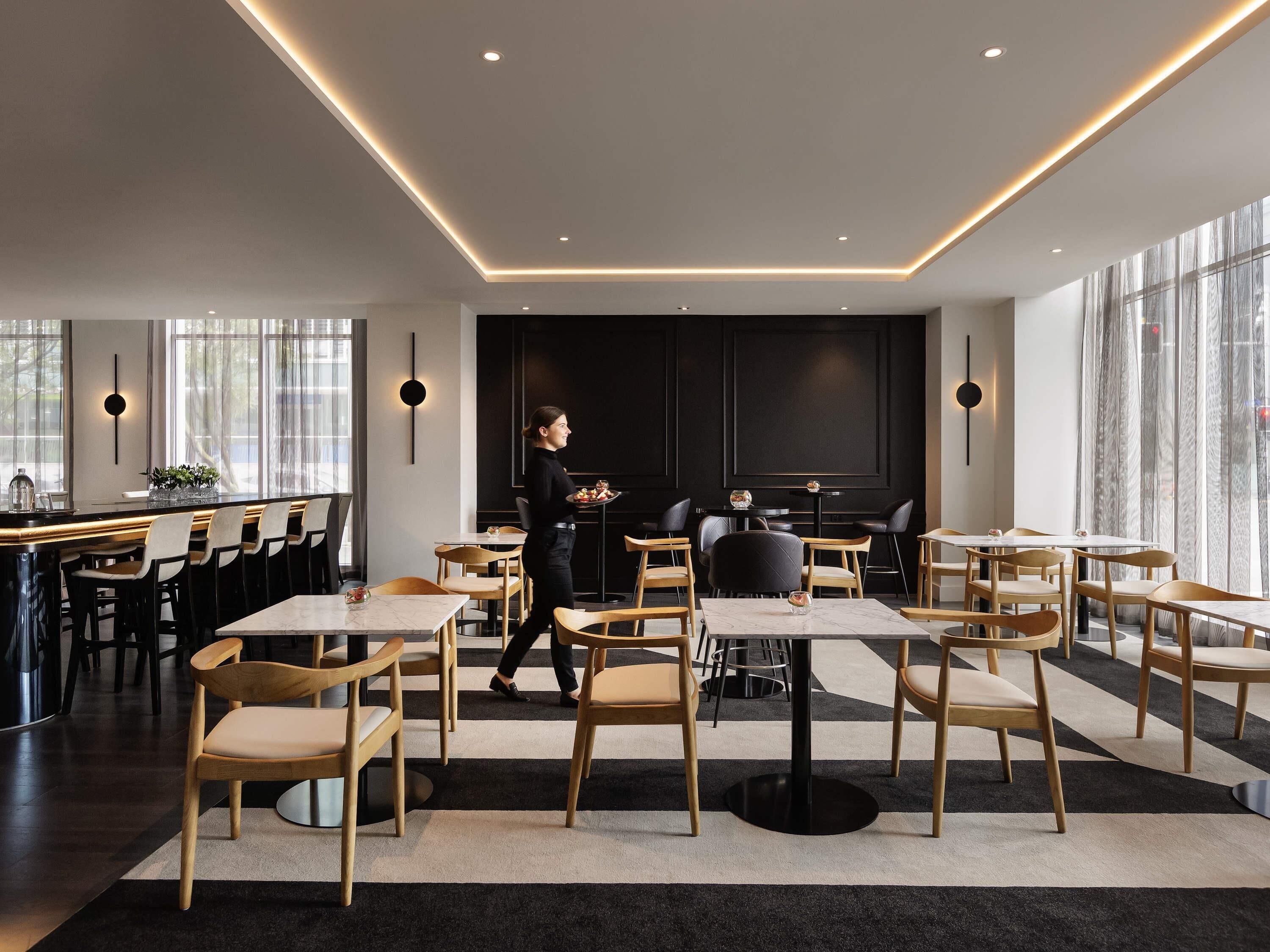 Un interno ristorante moderno con un'area bar, tavoli e sedie.