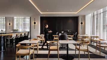 Un interno ristorante moderno con un'area bar, tavoli e sedie.