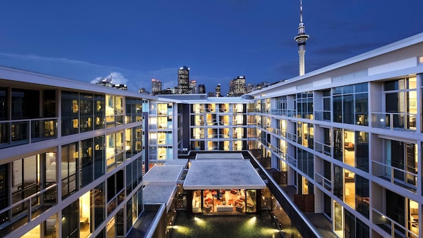 A modern hotel with multiple floors, a rooftop pool, and a view of the city skyline including a prominent tower. - Sofitel Auckland Viaduct Harbour (Auckland)