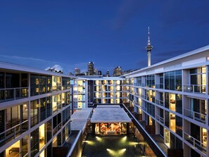 A modern hotel with multiple floors, a rooftop pool, and a view of the city skyline including a prominent tower. - Sofitel Auckland Viaduct Harbour (Auckland)