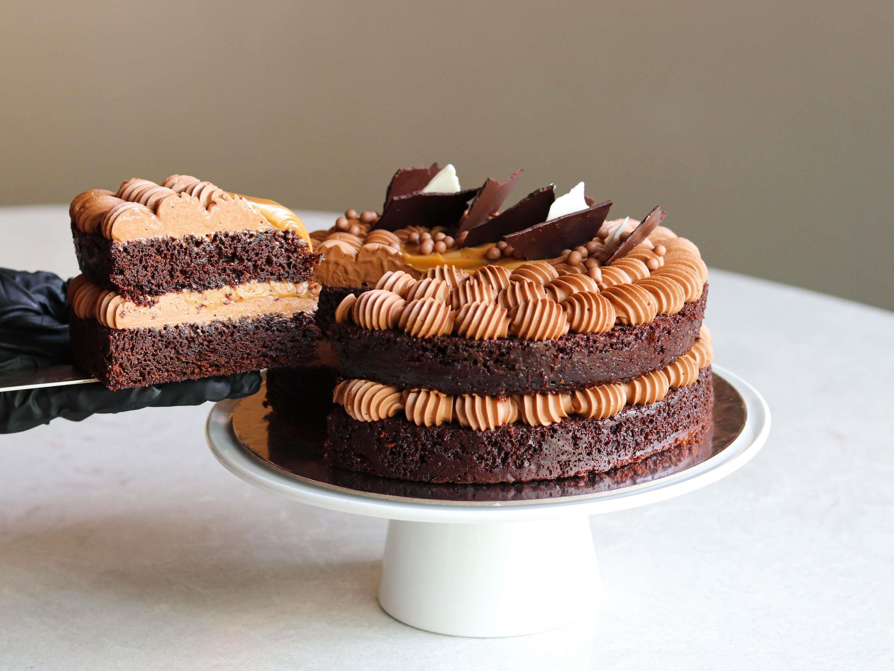 A multi-layered chocolate cake with a slice being served.