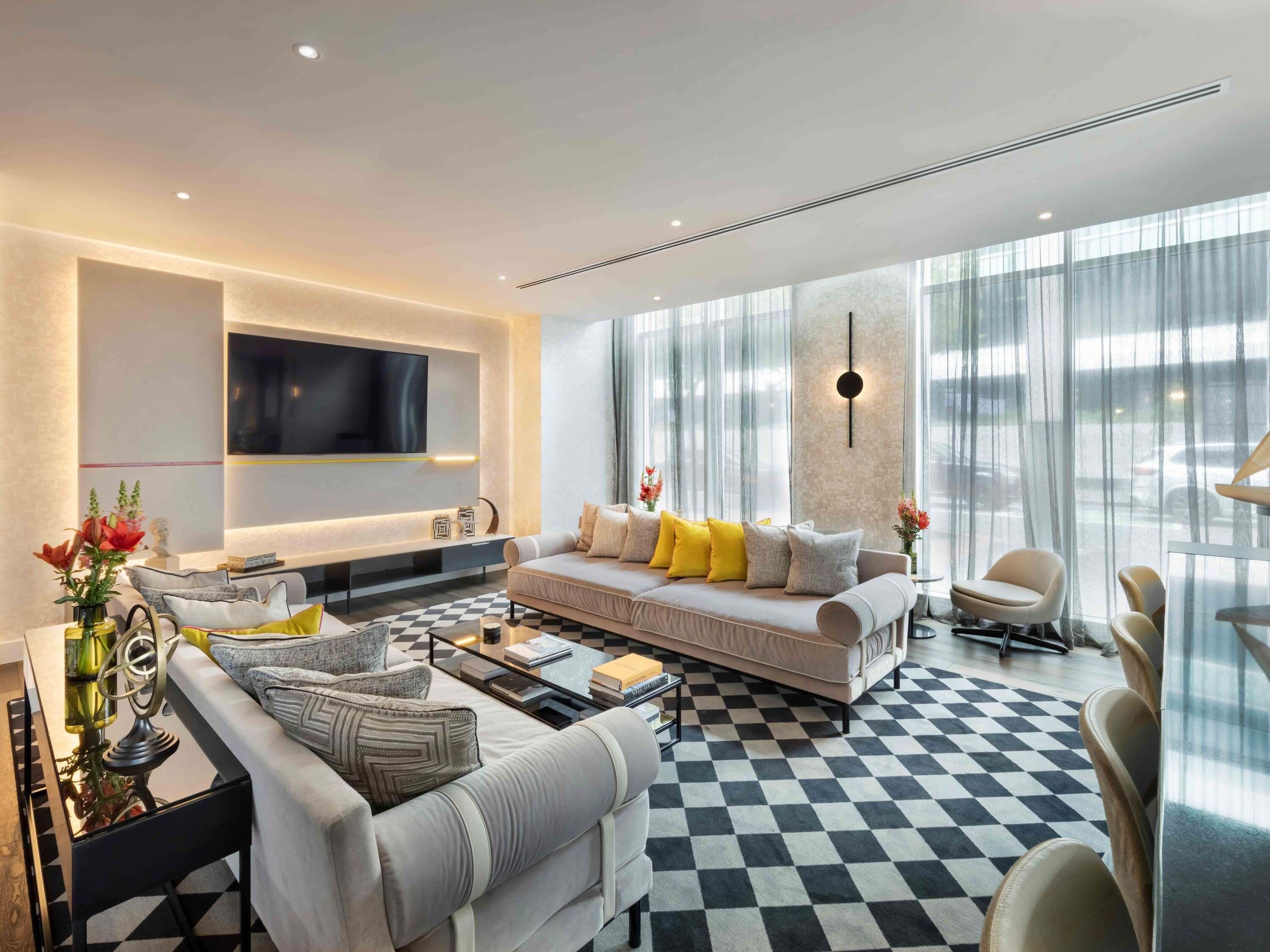 A modern living room with a sofa, coffee table, and TV mounted on the wall.