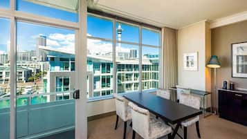 Un hotel moderno con una ventana grande, una mesa de comedor con sillas, una lámpara y un cuadro en la pared.