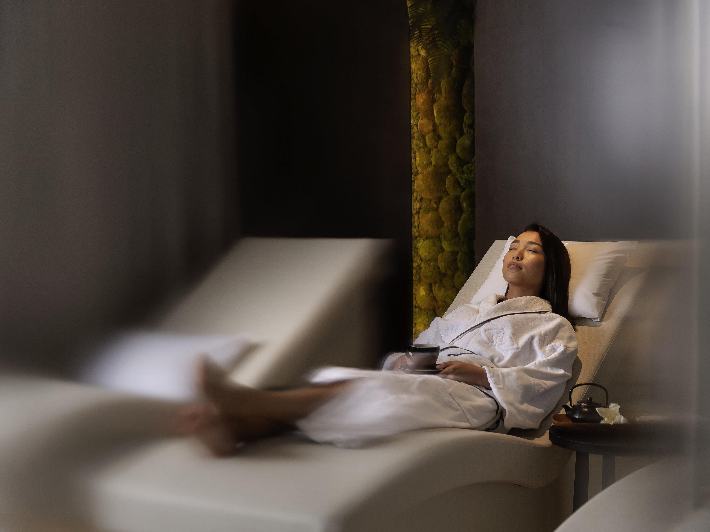 A person lying on a massage chair in a spa setting.