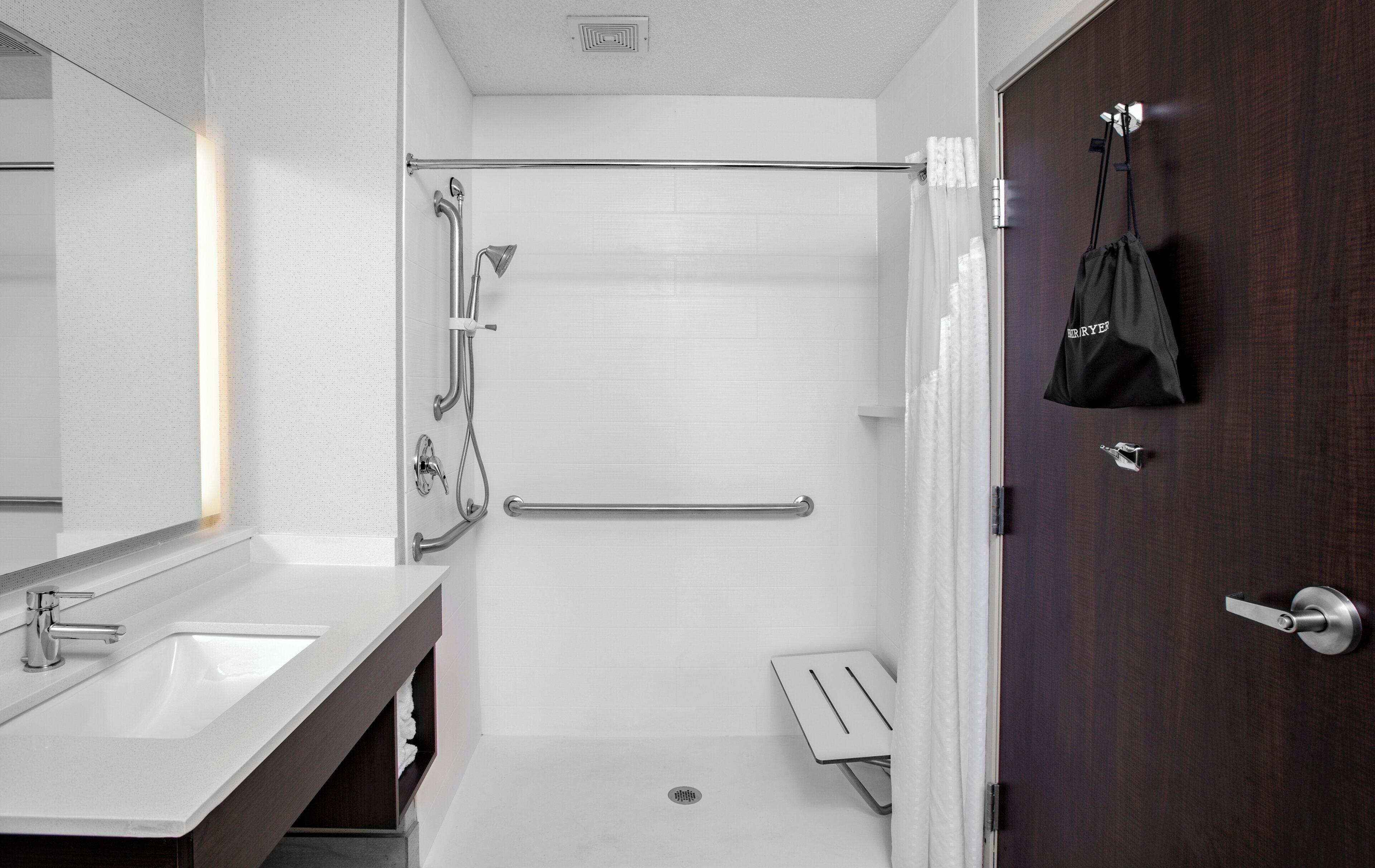 A modern bathroom with a shower, a toilet, a sink, and a mirror.