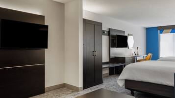 A hotel room with a bed, a desk, a chair, a TV, and a wardrobe.
