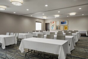 A conference room with multiple tables and chairs, a large window, and artwork on the wall. - Holiday Inn Express Hotel & Suites Altoona-Des Moines by IHG (Altoona)
