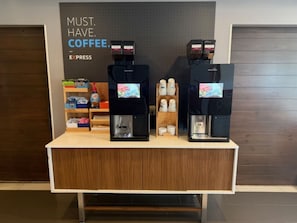 A coffee station with two espresso machines and a display of coffee cups and pods.