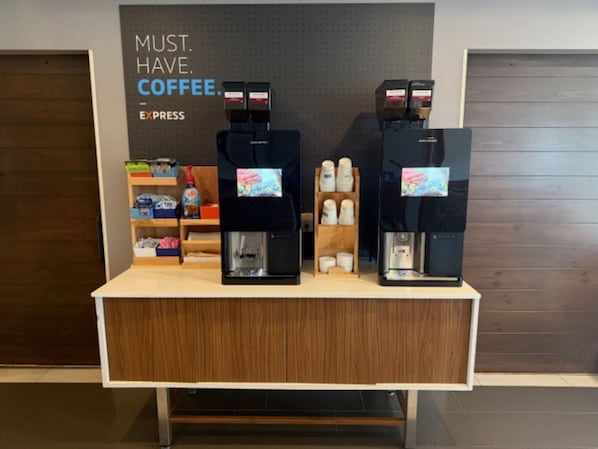 Una estación de café con dos máquinas de espresso y una exhibición de tazas y cápsulas de café.