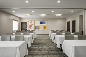 A conference room with tables and chairs, a patterned carpet, and artwork on the walls. - Holiday Inn Express Hotel & Suites Altoona-Des Moines by IHG (Altoona)
