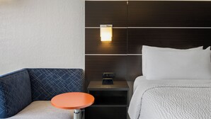 A hotel room with a bed, a nightstand, a table, and a chair.