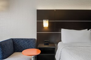 Una habitación de hotel con una cama, una mesita de noche, una mesa y una silla.