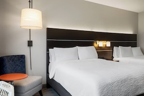 A hotel room with a bed, bedside lamps, a chair, and a small table. - Holiday Inn Express Hotel & Suites Altoona-Des Moines by IHG (Altoona)