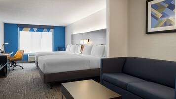 A hotel room with a bed, a sofa, a desk, and a chair.