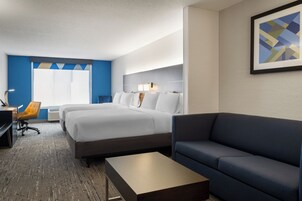 A hotel room with a bed, a sofa, a desk, and a chair.