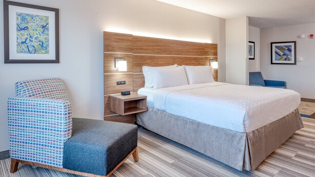 A hotel room with a bed, bedside table, chair, and artwork on the walls. - Holiday Inn Express & Suites Vandalia by IHG (Vandalia)
