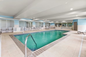 An indoor swimming pool with tiled flooring, a metal ladder, and seating areas with chairs and tables. - Holiday Inn Express & Suites Vandalia by IHG (Vandalia)