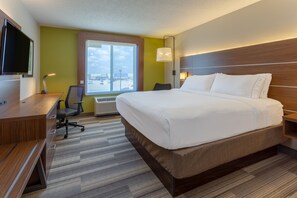 A hotel room with a large bed, a desk with a chair, a flat-screen TV, and a window with a view of the city. - Holiday Inn Express & Suites Vandalia by IHG (Vandalia)