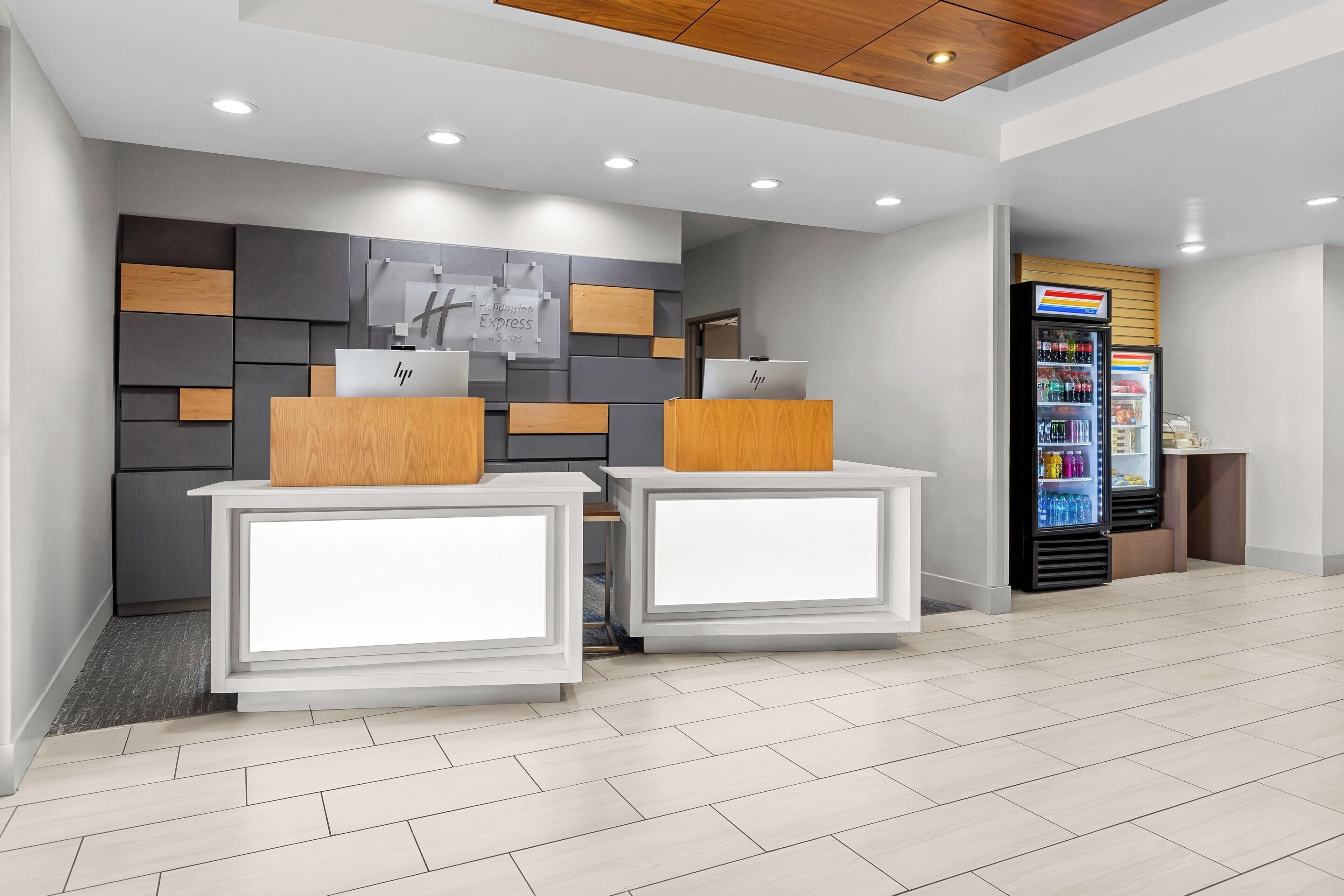 A reception area with two counters, a wall-mounted sign, a vending machine, and a tiled floor.