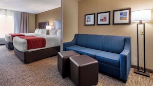 A hotel room with two beds, a blue sofa, and a floor lamp. - Comfort Inn & Suites Goodland (Goodland)