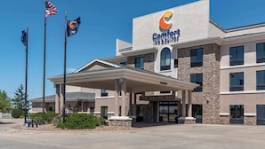 A Comfort Inn & Suites building with a covered entrance, American flags, and a clear blue sky. - Comfort Inn & Suites Goodland (Goodland)