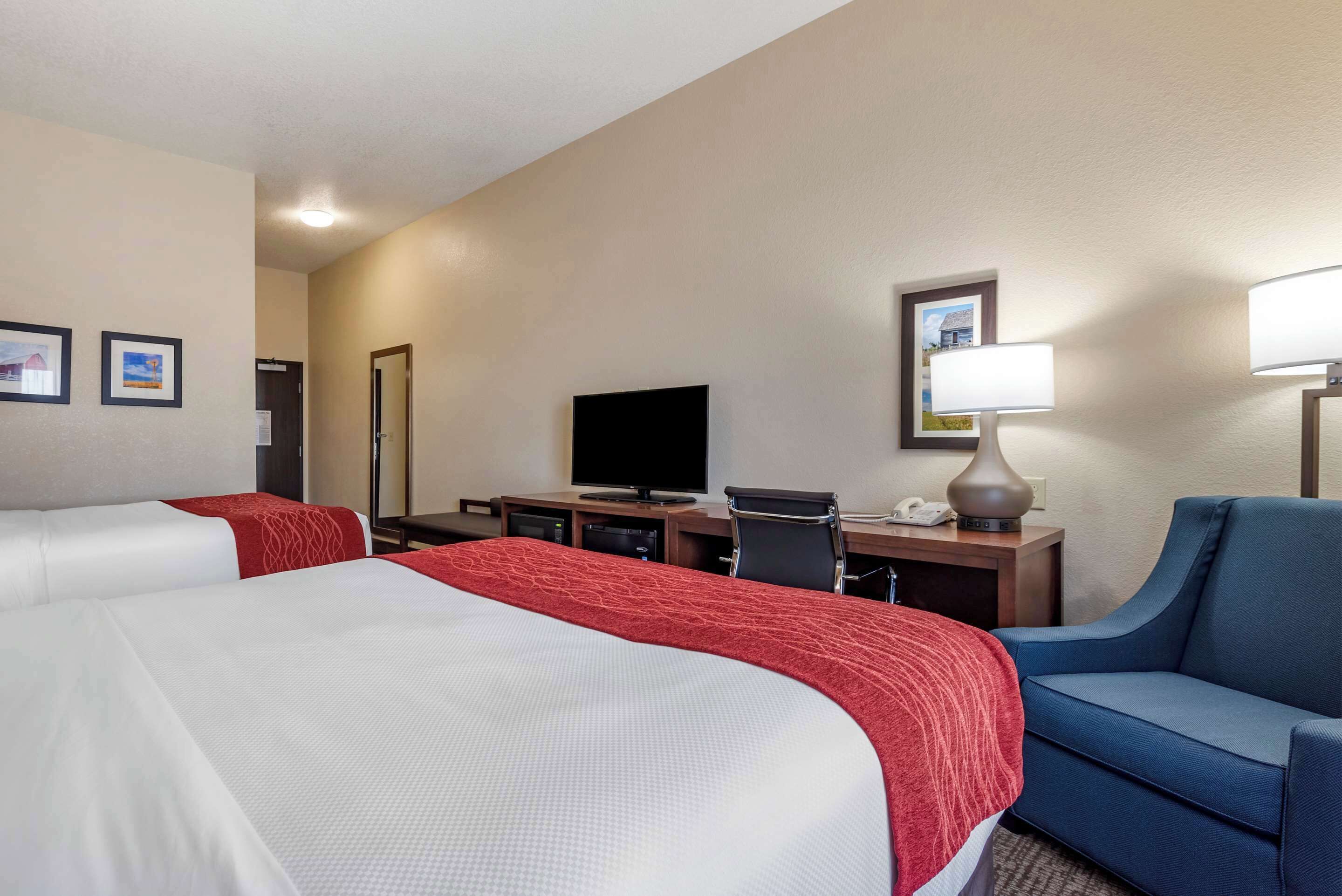 A hotel room with two beds, a desk with a computer, a television, and a chair.