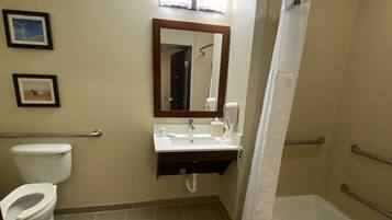 A bathroom with a toilet, sink, mirror, and bathtub.