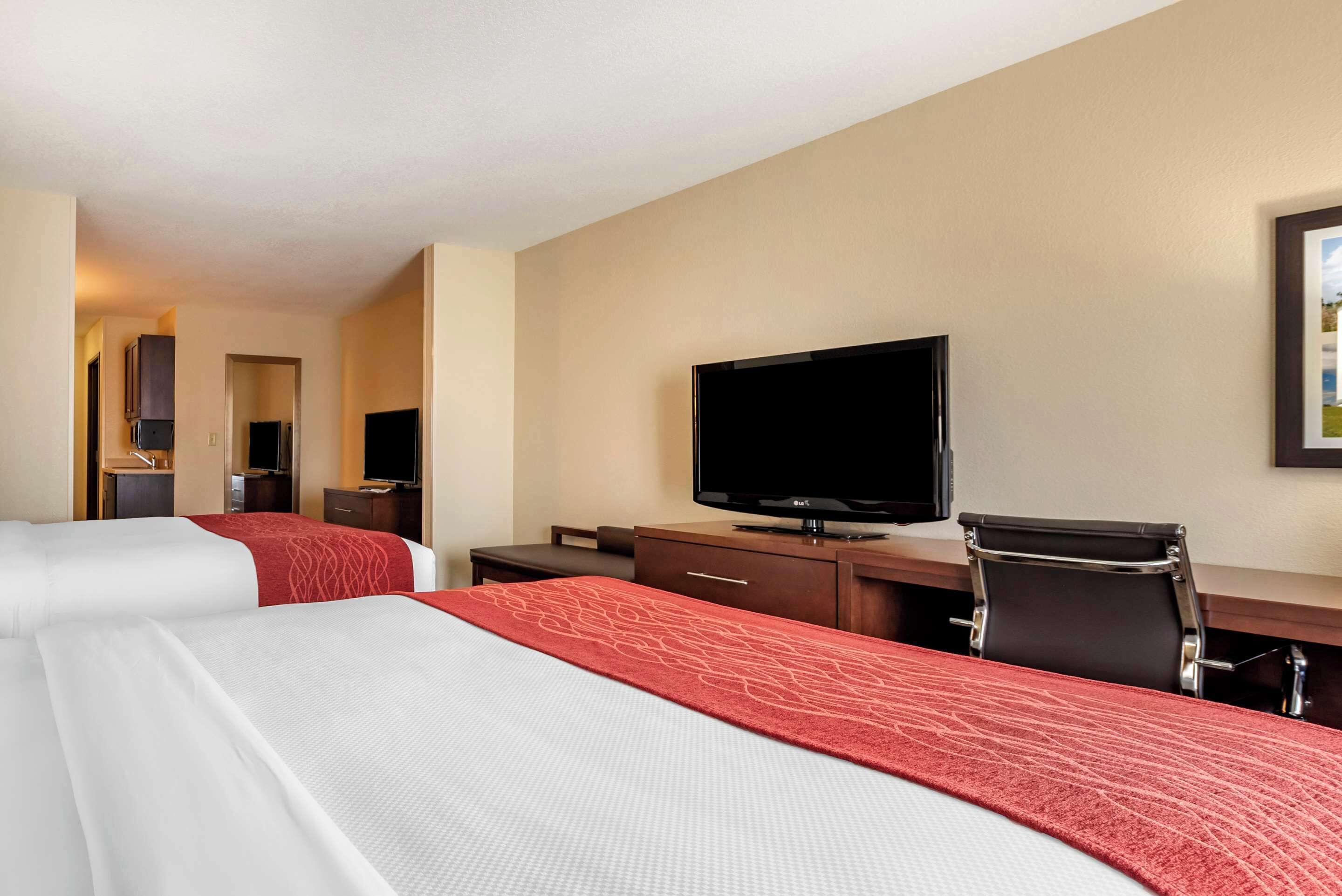 A hotel room with two beds, a desk with a television, and a chair.