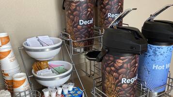 A coffee station with dispensers labeled 'Decaf' and 'Regular', bowls of coffee beans, and containers of creamer and sugar.