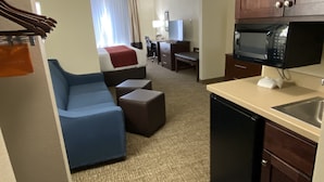 A hotel room with a kitchenette, a sofa, a desk, and a television. - Comfort Inn & Suites Goodland (Goodland)