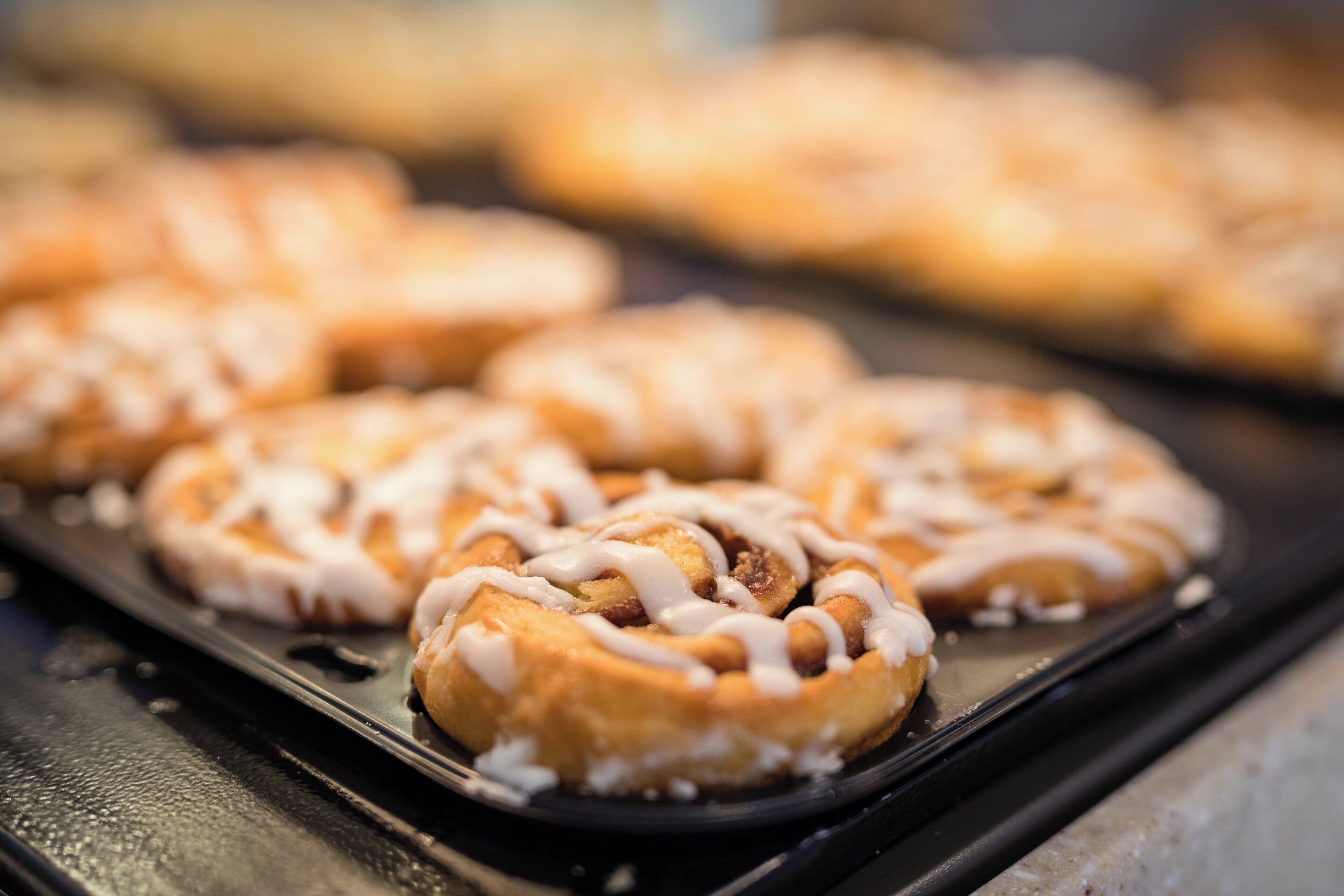 A tray of baked goods with icing on a black surface.