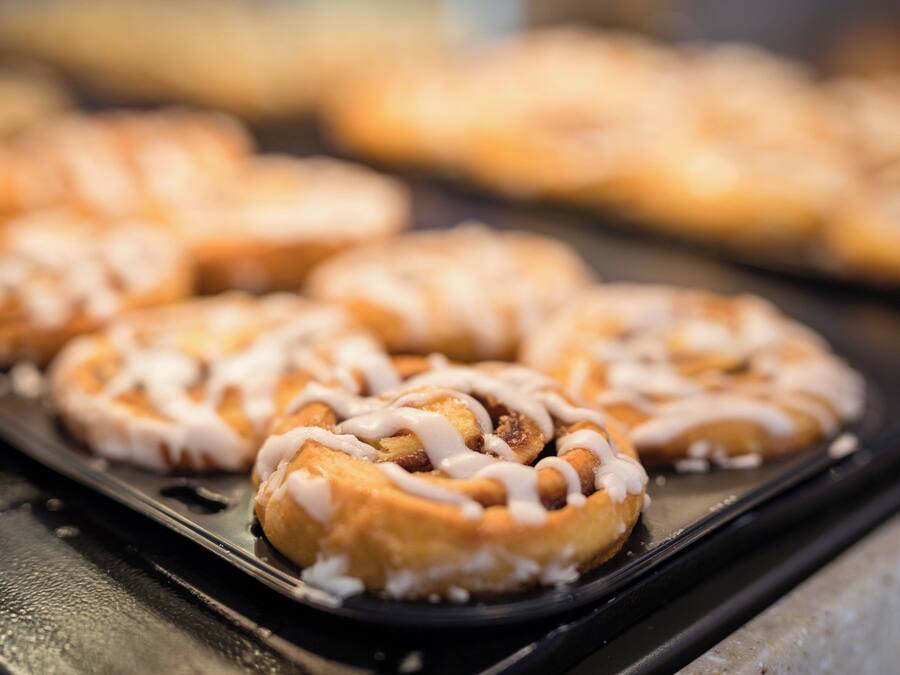 A tray of baked goods with icing on a black surface.