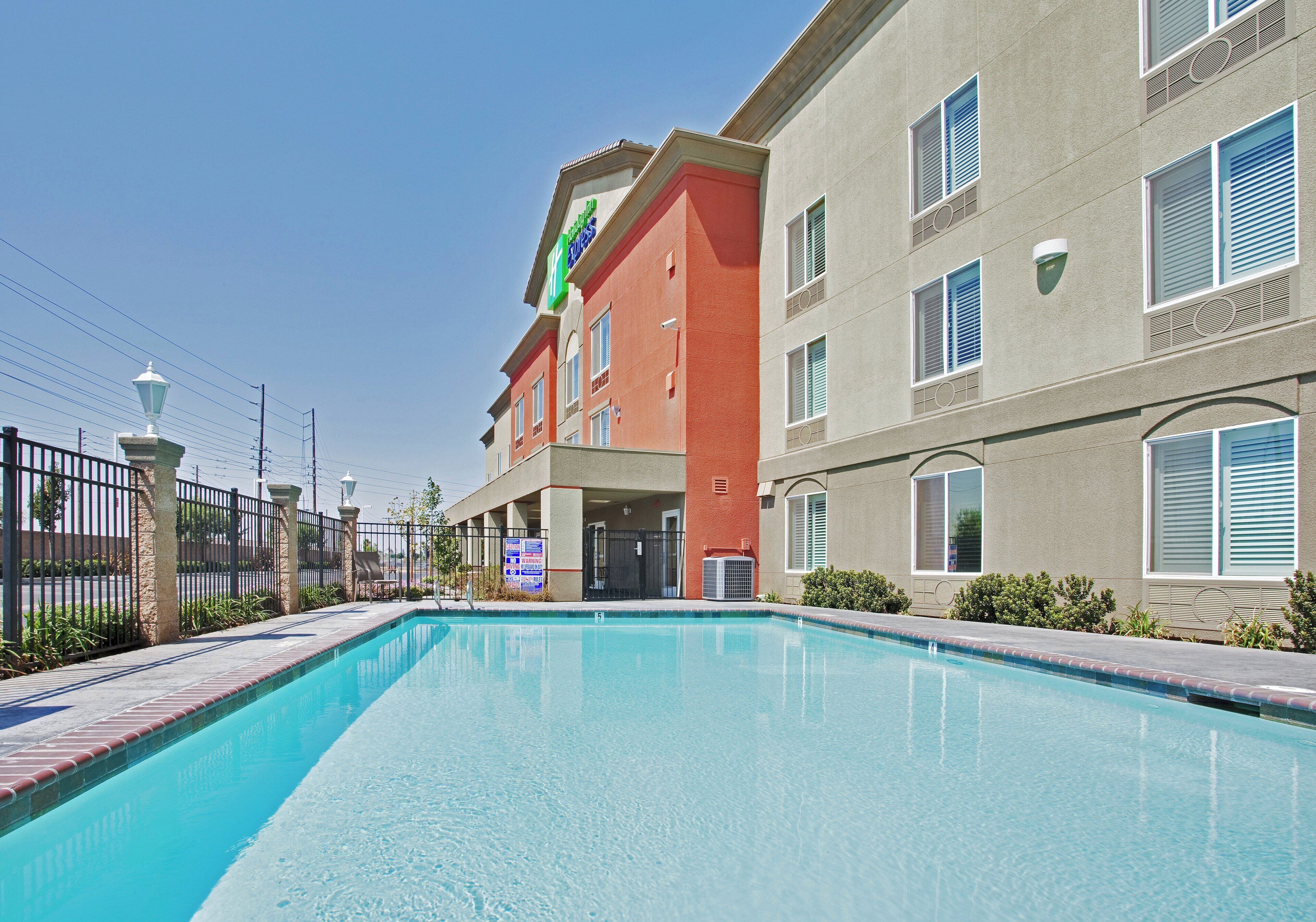 A hotel with a swimming pool, a fenced area, and a signboard.