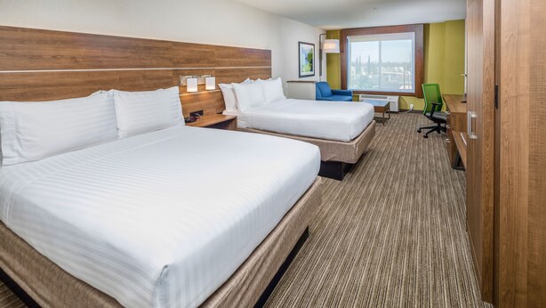 A hotel room with two beds, a desk, a chair, and a large window. - Holiday Inn Express and Suites Modesto by IHG (Modesto)