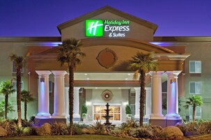 Et Holiday Inn Express & Suites hotel med en klassisk facade, palmer og en springvand i indgangen.