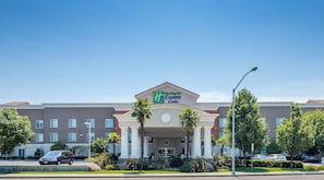 Edificio di un Holiday Inn Express & Suites con ingresso centrale, palme e cielo azzurro.