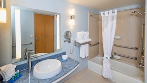 A bathroom with a sink, mirror, towel rack, and a walk-in shower with grab bars. - Holiday Inn Express and Suites Modesto by IHG (Modesto)