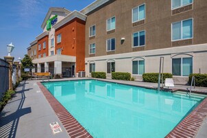 Hotel com piscina, área de estar externa e céu claro.