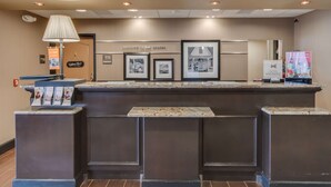 A reception desk with a marble top, framed pictures on the wall, a lamp, and a sign that reads "welcome to Las Cruces." - Hampton Inn & Suites Las Cruces I-25 (Las Cruces)