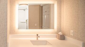 A bathroom with a large mirror, a sink, and a towel holder.