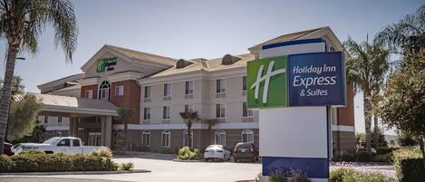 A Holiday Inn Express & Suites building with a parking lot and palm trees.