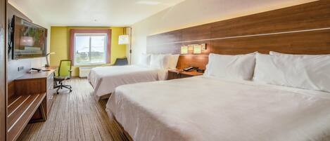 A hotel room with two beds, a desk, a chair, a TV, and a window with curtains.
