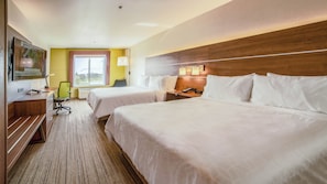 Hotelkamer met twee bedden, een bureau, een stoel, een televisie en een raam met gordijnen.