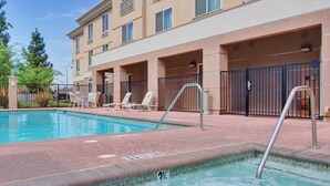 A swimming pool with a tiled edge, a metal ladder, and lounge chairs.