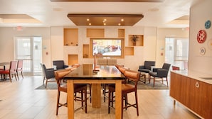 A conference room with a long table, multiple chairs, and a television screen displaying a scene.