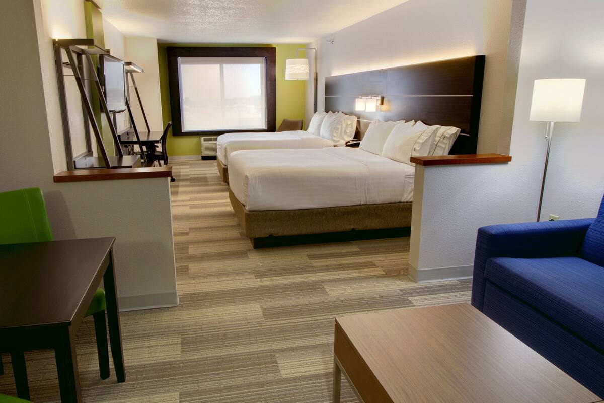 A hotel room with a bed, a desk, a chair, and a sofa.